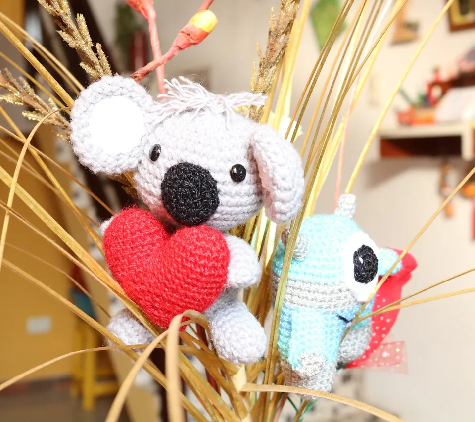 Amigurumi de koala tejido a crochet abrazando un corazón rojo